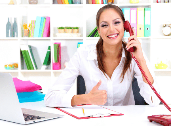 A woman sitting at her desk talking on the phone.